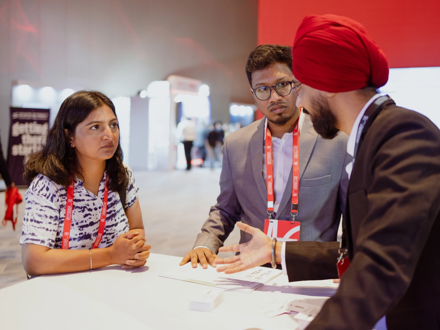 Several men discussing around a table and looking at monitor screen.