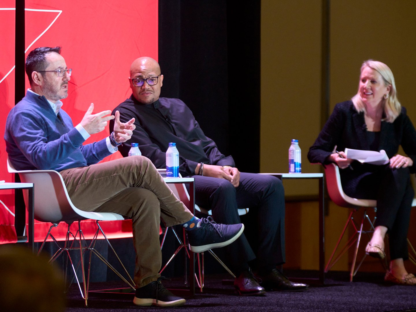 Panelists engaged in discussion on stage in front of a seated audience.