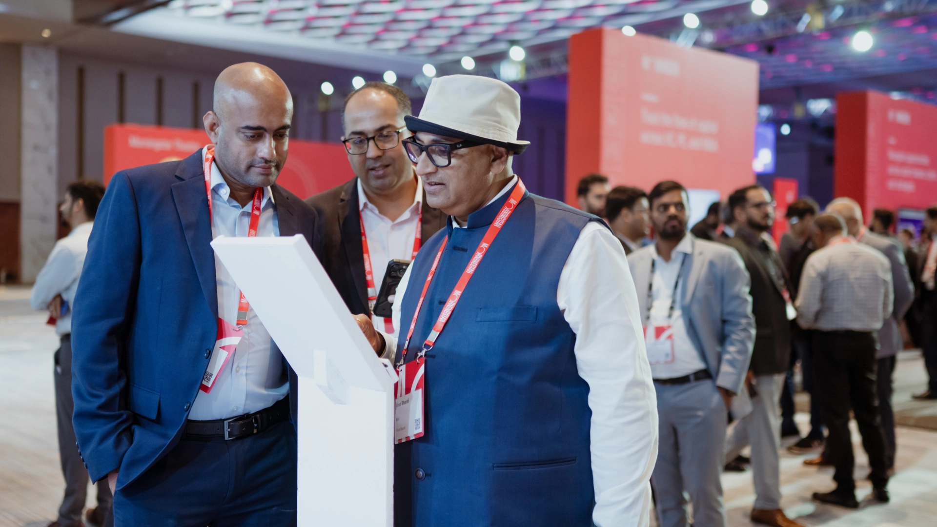 Several men discussing standing in front of a kiosks. 