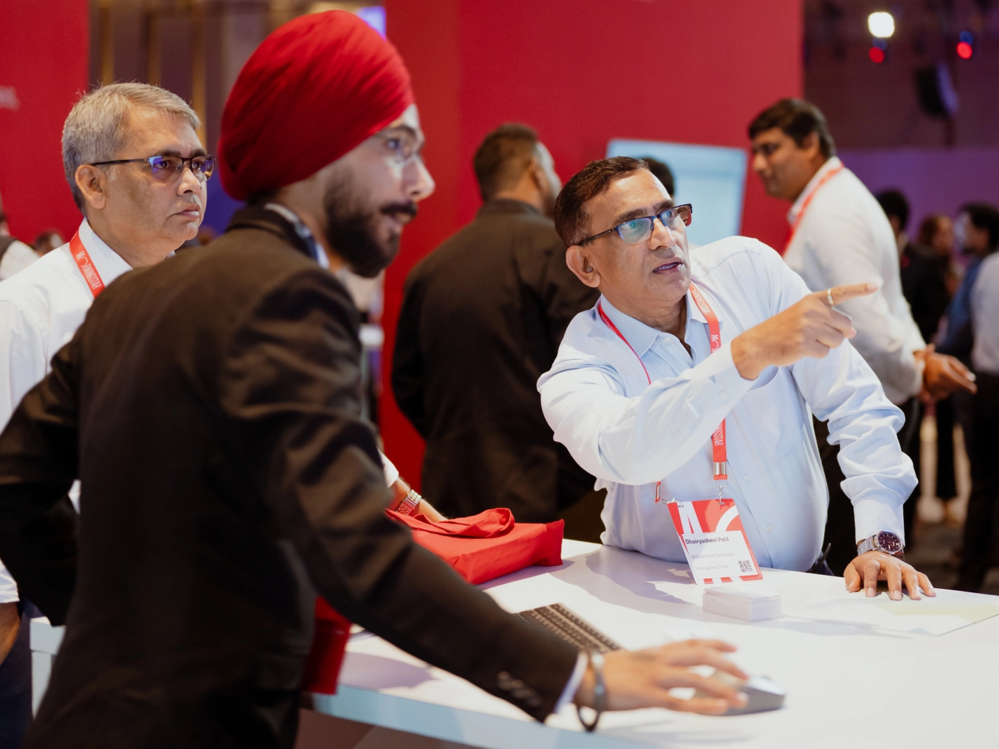 Several men discussing around a table and looking at monitor screen.