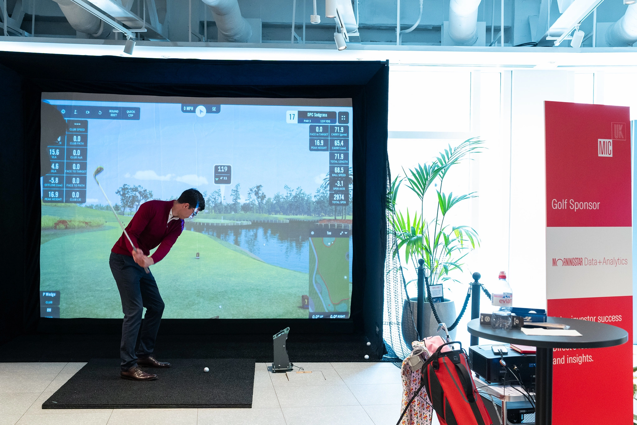 A gentlemen swing golf club at a golf simulator. 