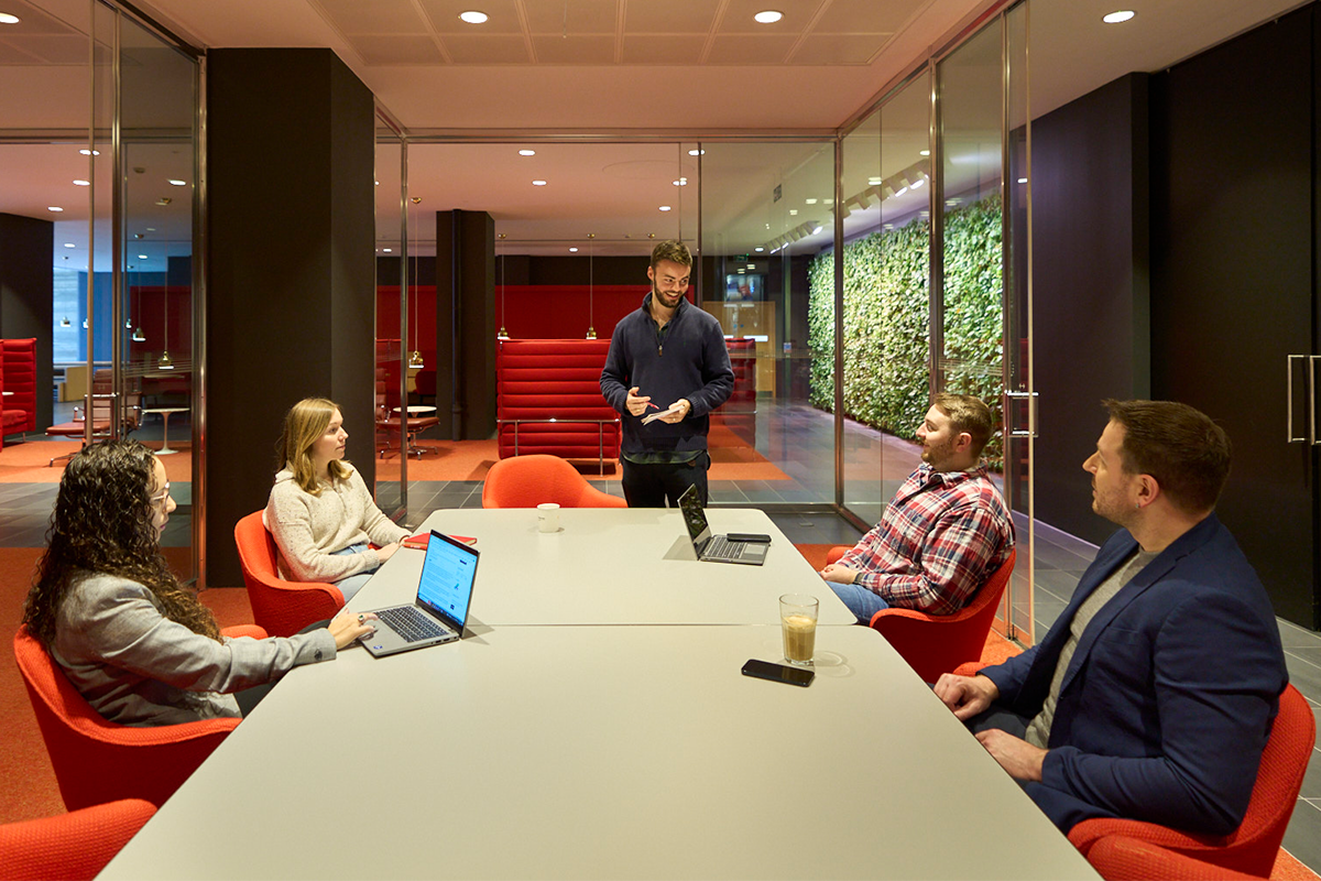 Morningstar employees collaborating in a small group meeting with a colleague presenting in a conference room.