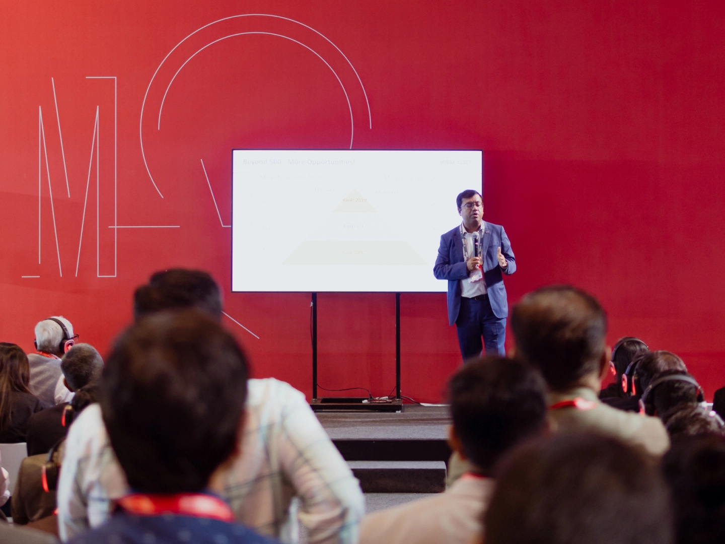 Speaker speaking in front of an audience on stage.