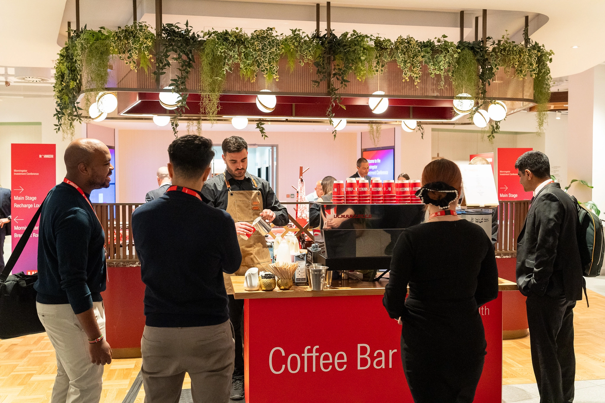 Multiple people standing in front of coffee bar to grab coffee. 